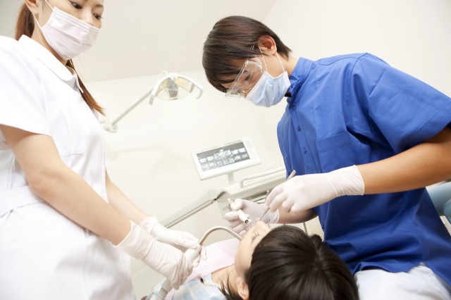 女性患者の治療をする男性歯科医と歯科衛生士